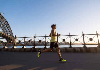 A man running on the road near a bridge.