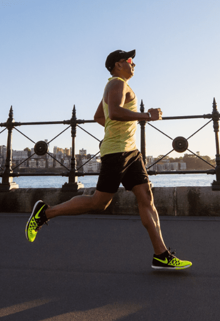 A man running on the street near a bridge.